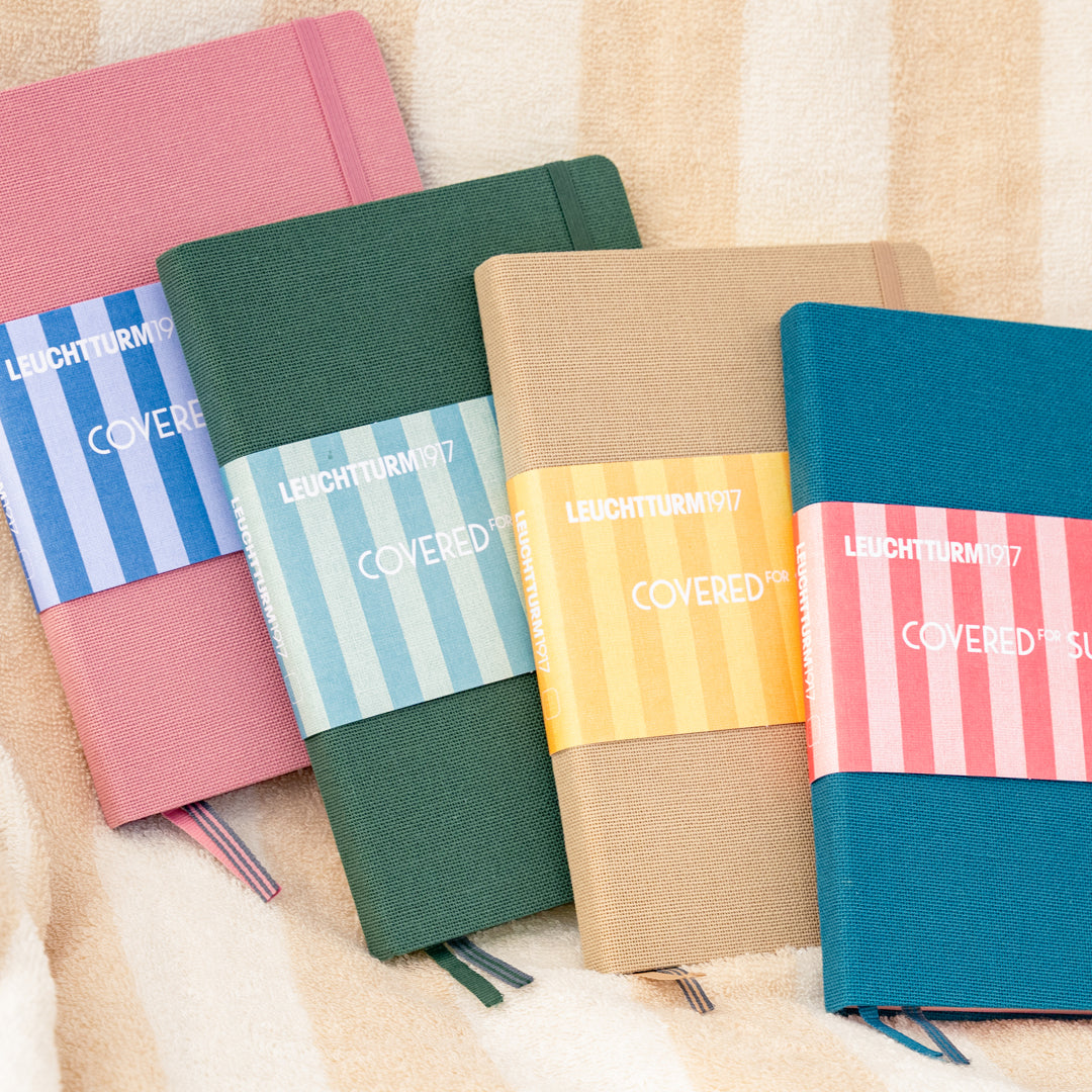 Five colorful notebooks with striped covers on a textured surface