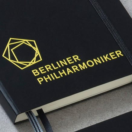 Black notebook with 'Berliner Philharmoniker' logo in yellow on a gray surface