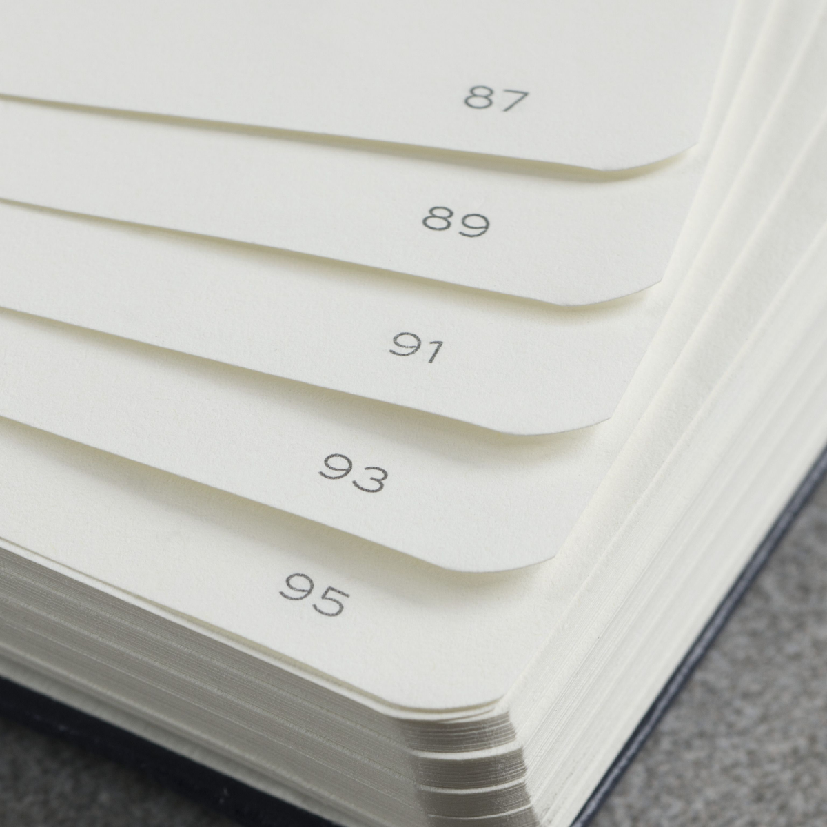 Stack of white papers with numbers printed on them, lying on a textured surface.