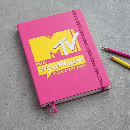 Pink notebook with MTV logo and text on a gray surface