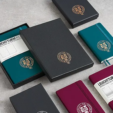 Collection of notebooks with embossed logos on a gray surface