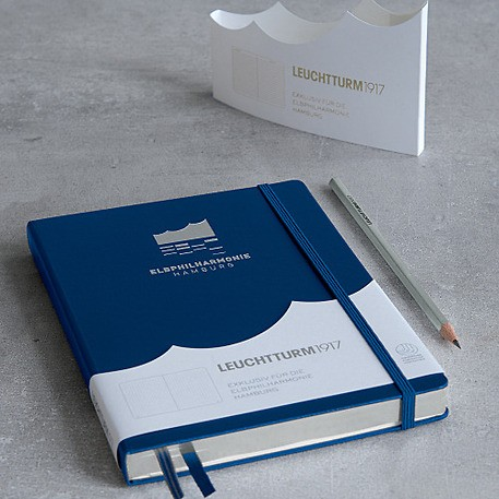 Blue and white notebook with a pencil on a gray surface, featuring Leuchtturm branding.