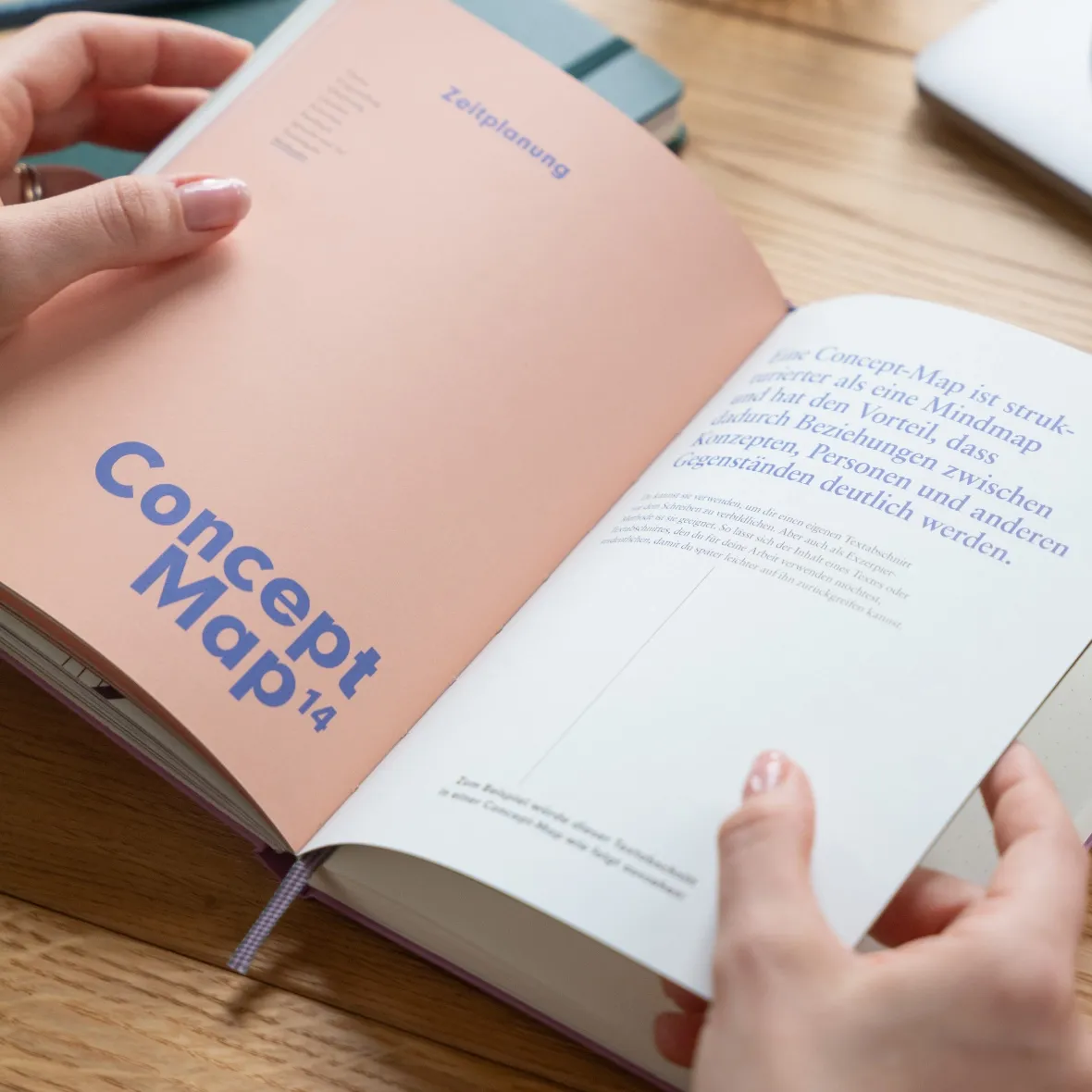 Open book titled 'Concept Map 14' held by hands on a wooden surface