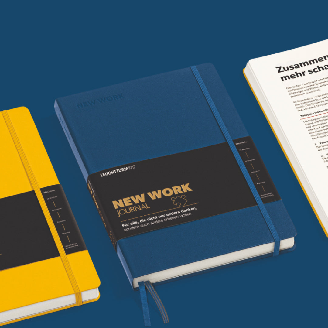 Two notebooks, one blue and one yellow, with a visible 'New Work' label on a blue background.