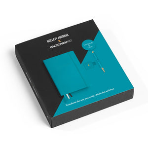 Teal bullet journal notebook with black cover in a box packaging on a white background