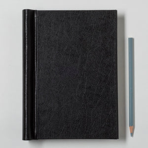 Black leather notebook with a pencil on a light gray background