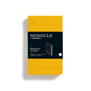 Yellow notebook with black label featuring 'Monocle' branding on a white background