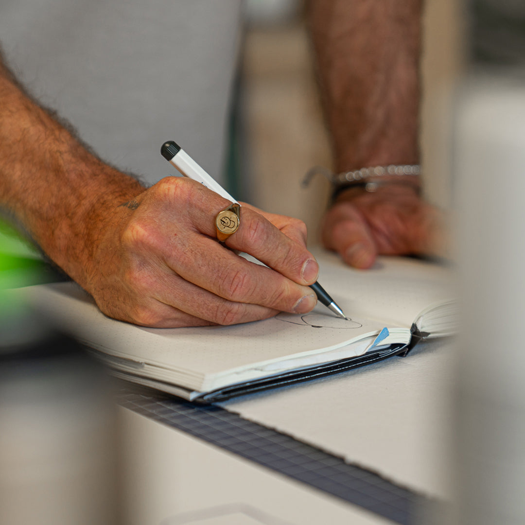 Person writing in a notebook with a pen, blurred background