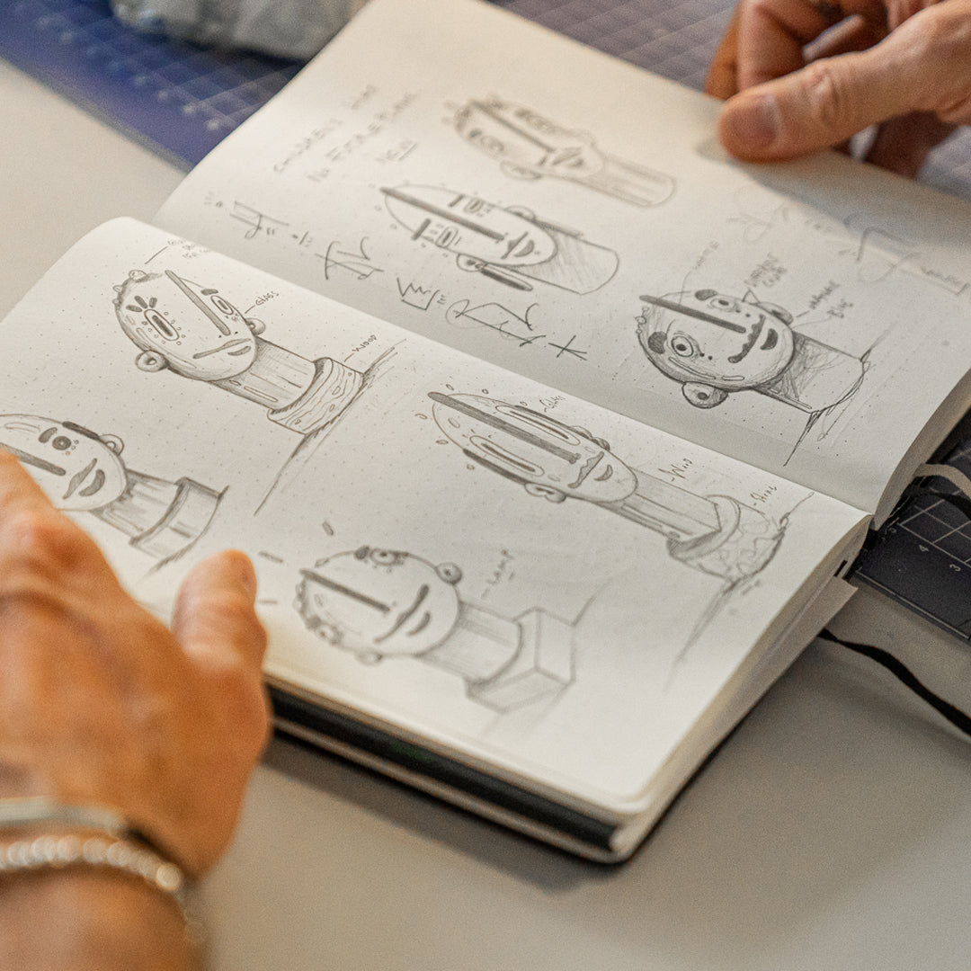 Person holding a notebook with mechanical drawings on a desk