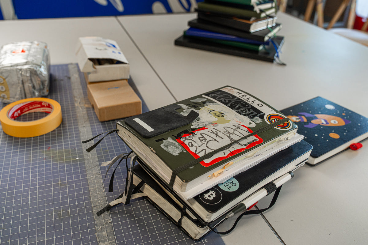Stack of notebooks with stickers on a table with tape and other items