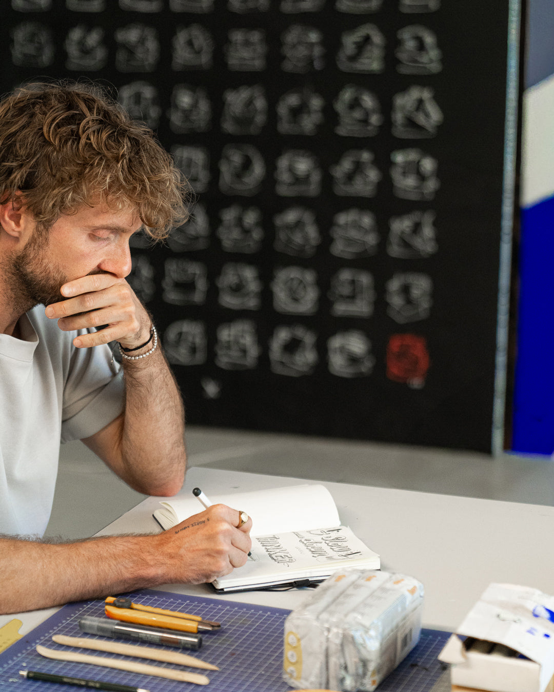 Man sitting at a desk with stationery items, looking thoughtful