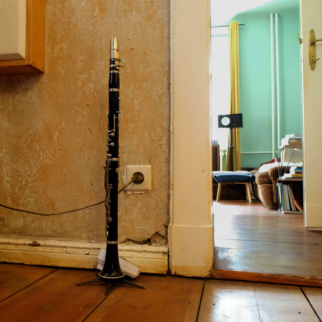 Clarinet on a stand against a textured wall with a room in the background
