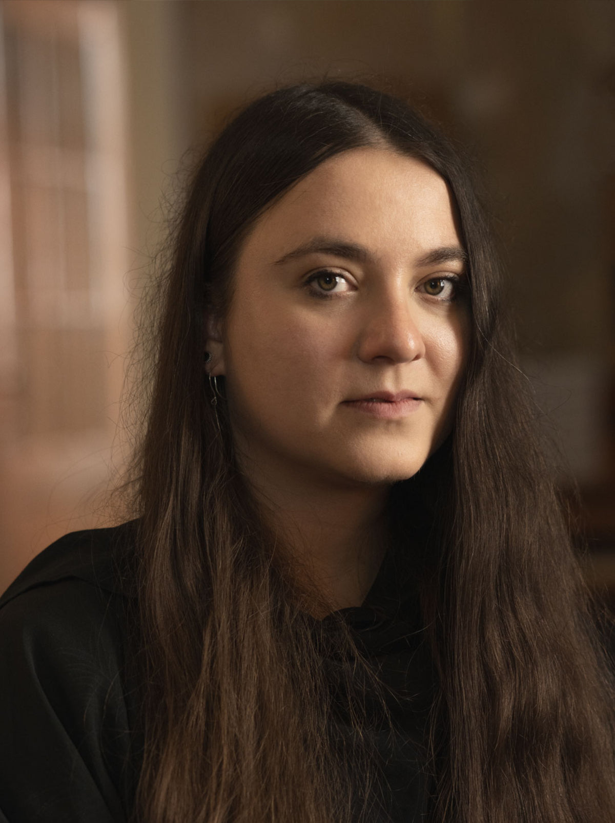 Portrait of a woman with long dark hair in a softly blurred indoor setting