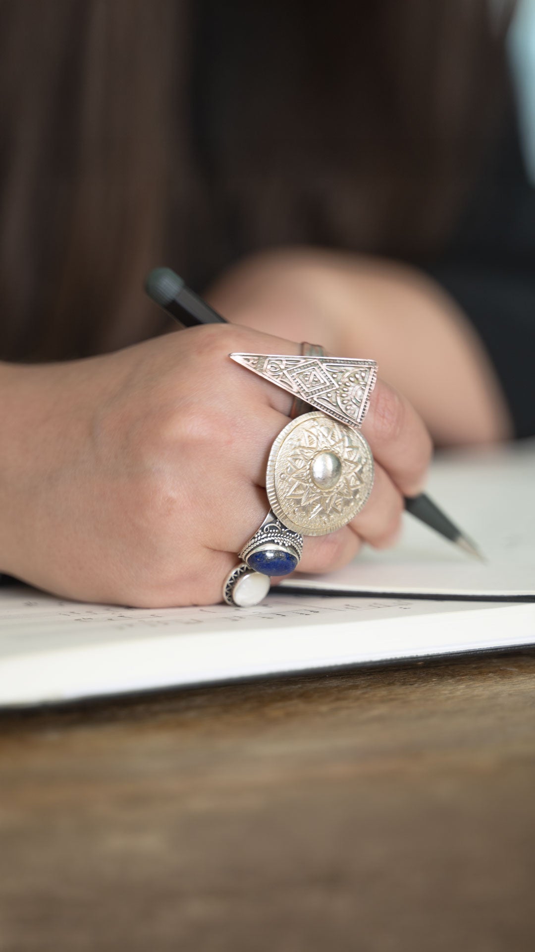 Person's hand with rings holding a pen on a piece of paper