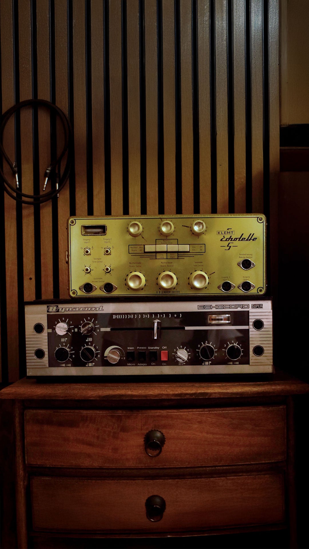 Vintage electronic equipment on a wooden surface with a striped wall background
