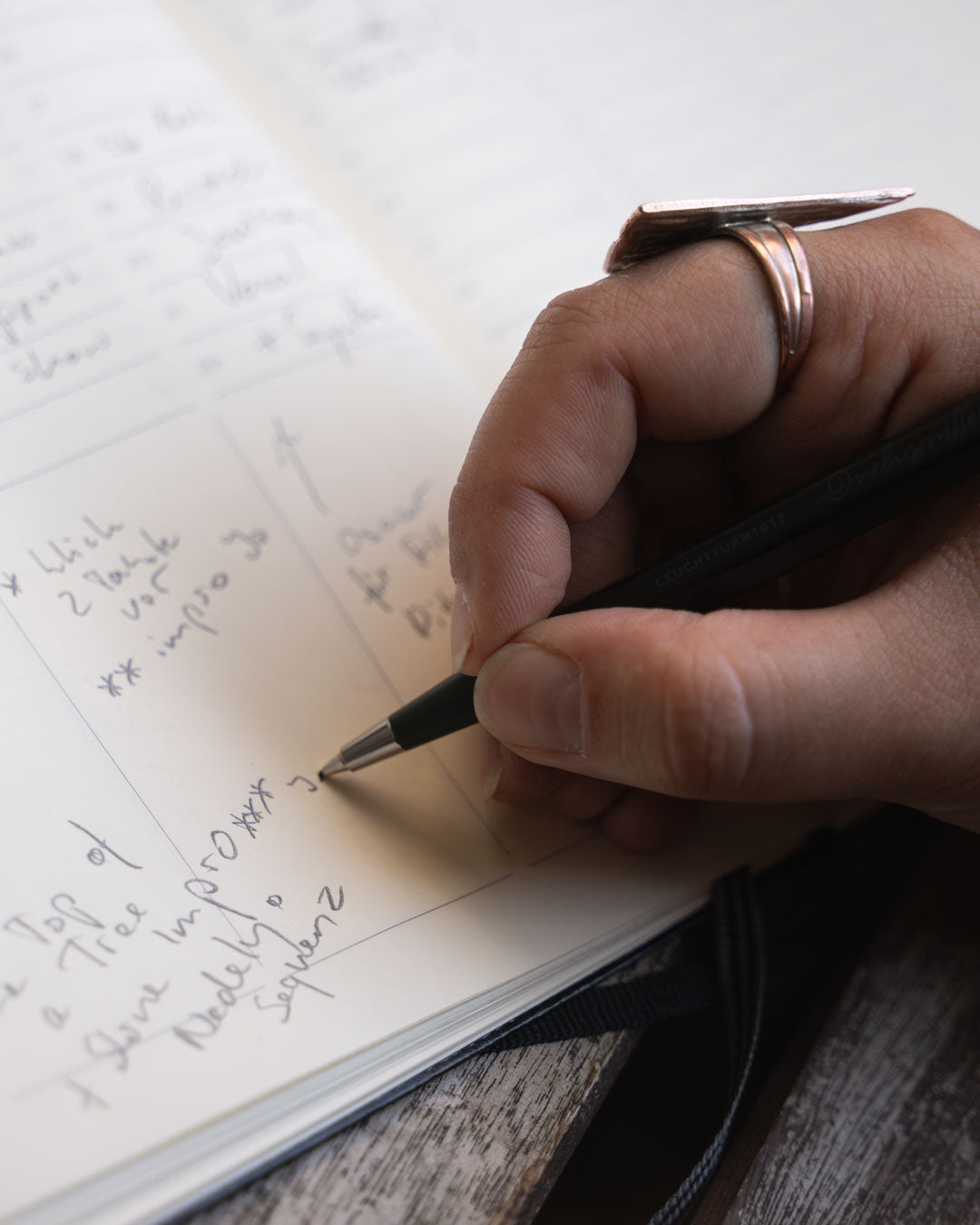 Hand writing in a notebook with a pen on a wooden surface
