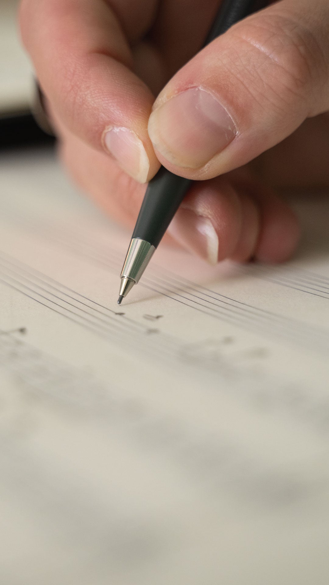 Hand holding a pen over sheet music