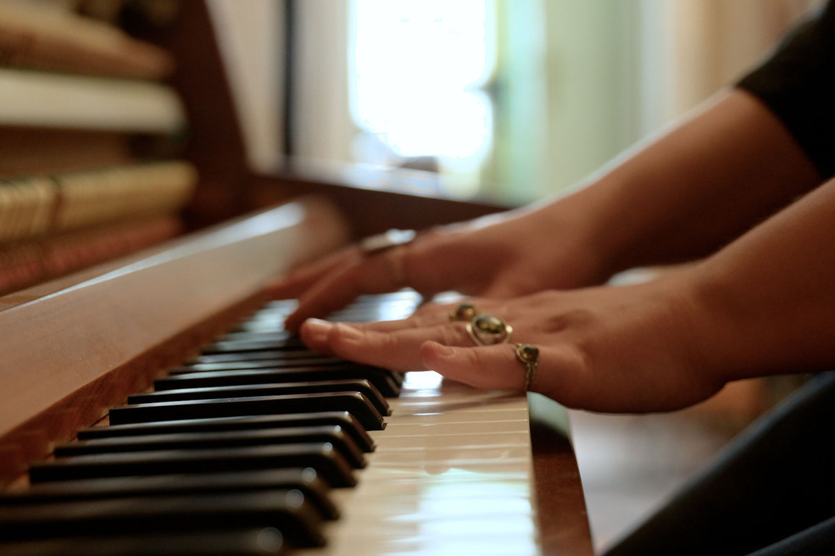 Close-up of hands playing a piano with a blurred background