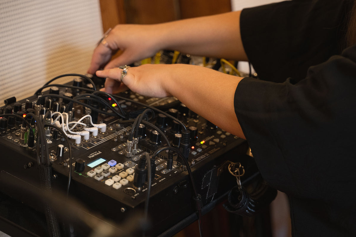 Person adjusting electronic equipment with visible wiring and components.