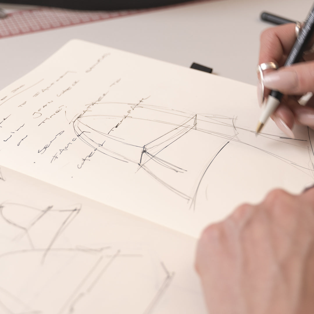 Person sketching a design on a piece of paper with a pen.
