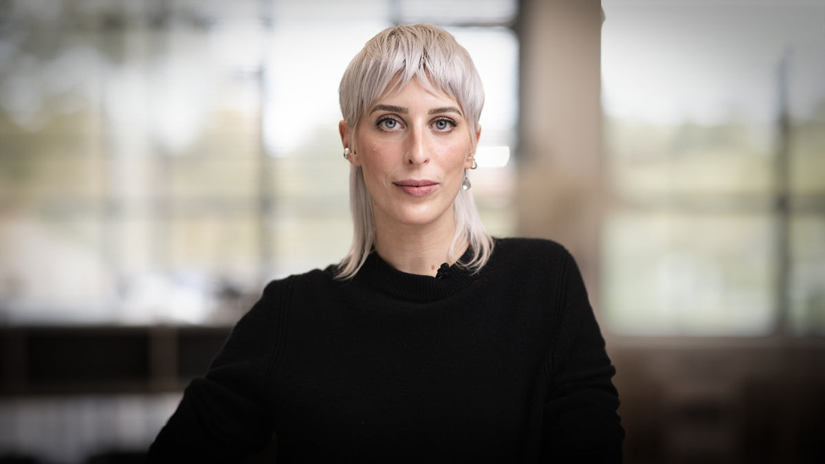 Woman with short blonde hair wearing a black sweater in an indoor setting
