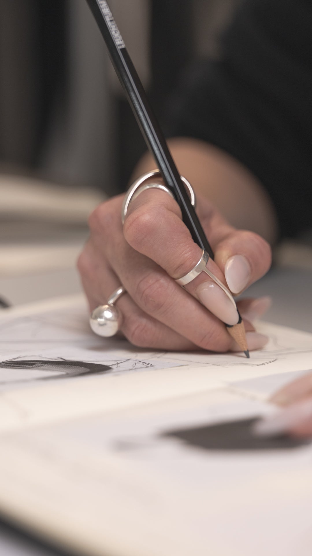 Close-up of a hand with a ring holding a pen, writing on paper.