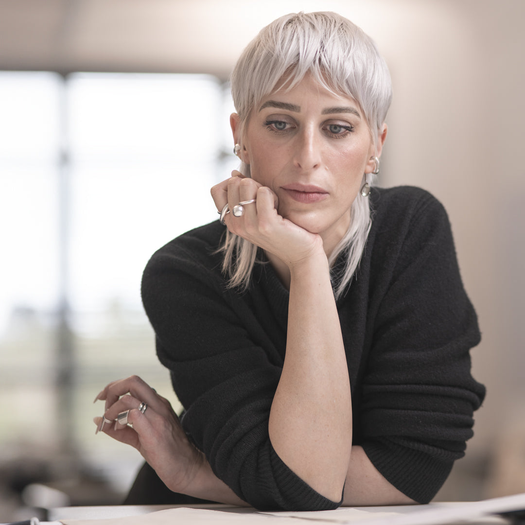 Woman with short blonde hair wearing a black sweater indoors