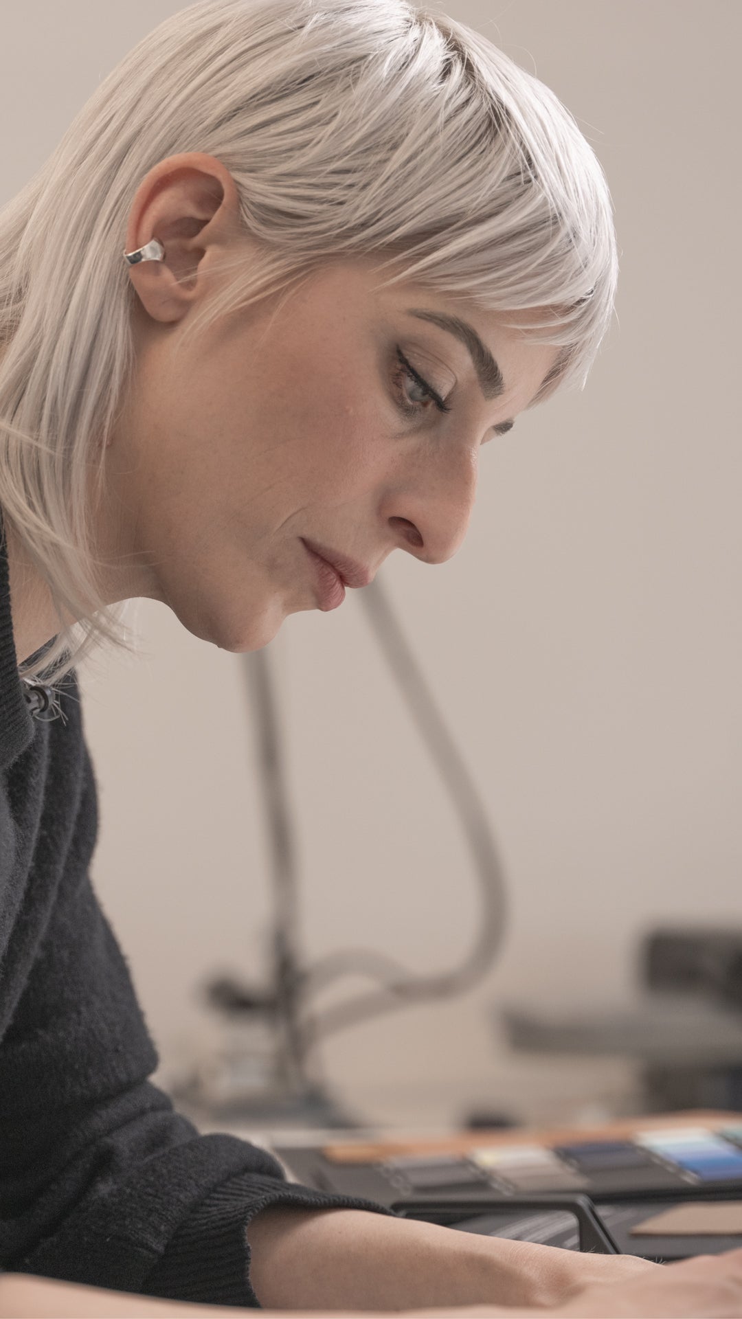 Person with short blonde hair looking down at a table with a blurred background