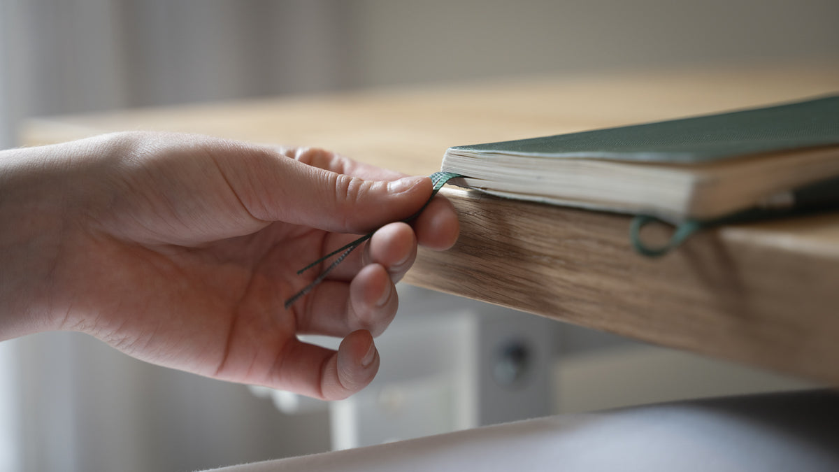 Hand holding a bookmark on a wooden surface