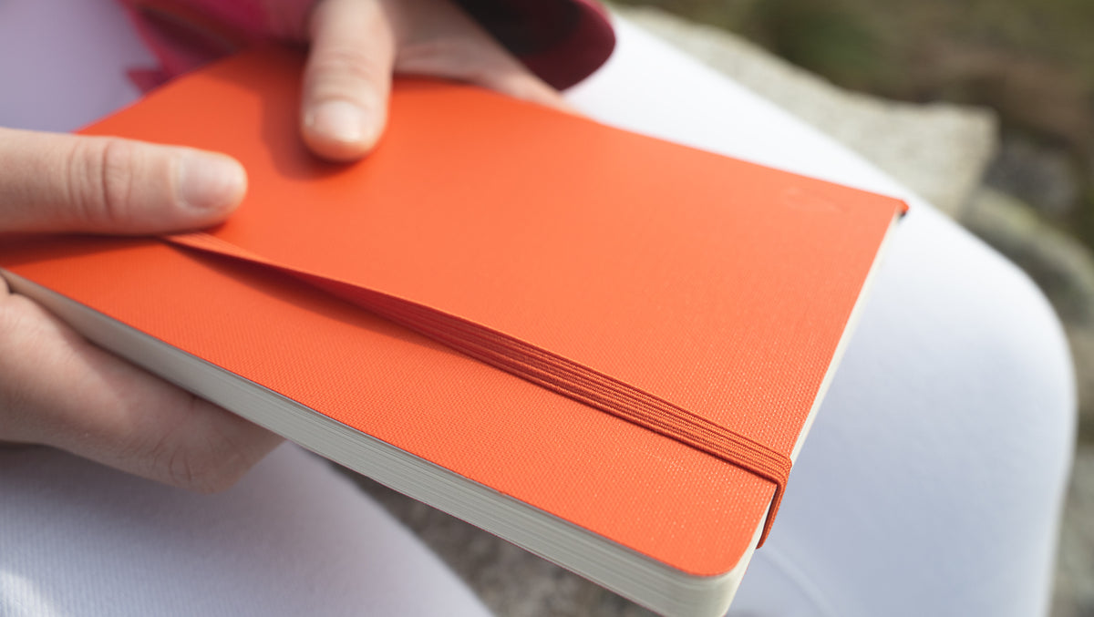 Person holding an orange notebook with a blurred background