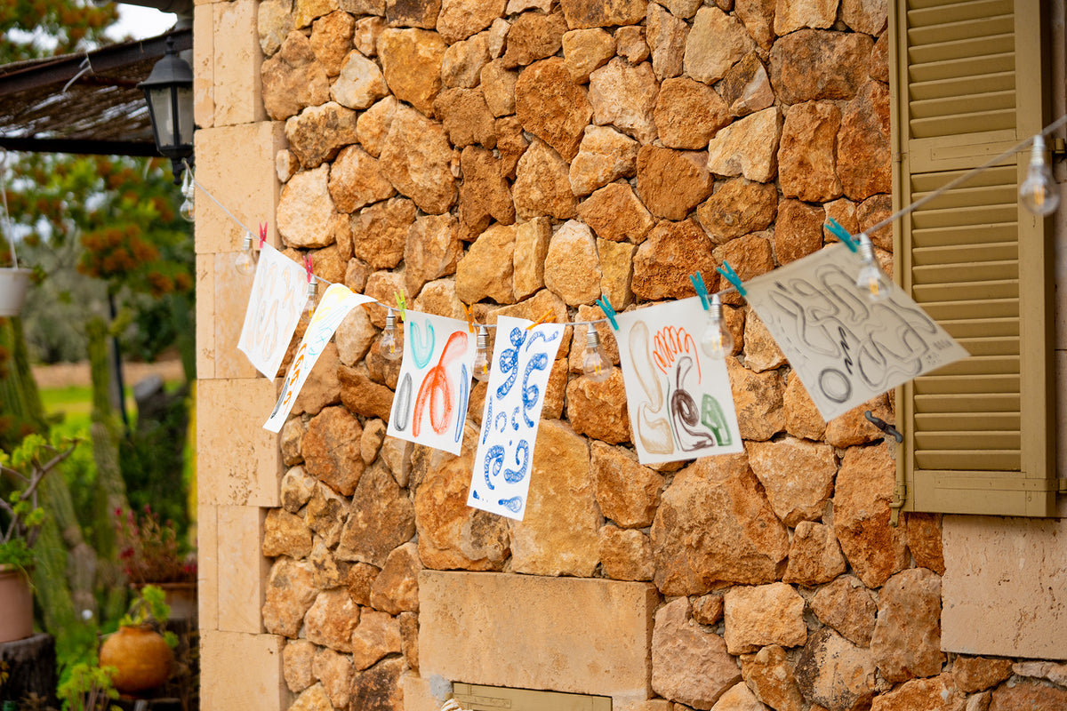 Colorful drawings on paper clips against a stone wall