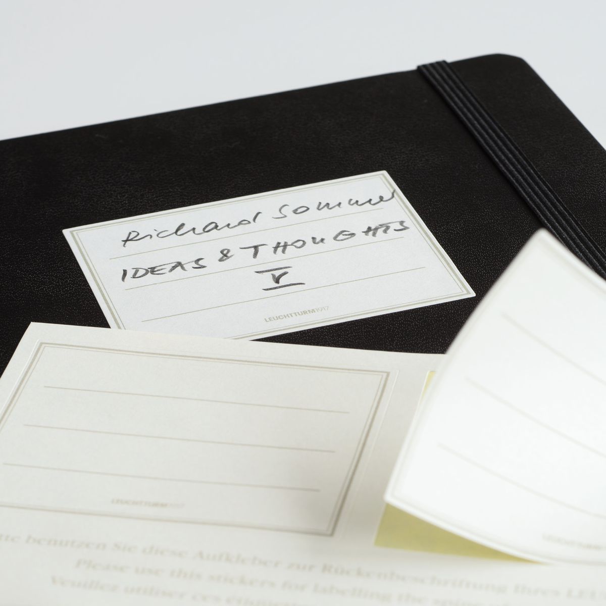 Black notebook with white cards labeled 'Richard Solomon' and 'Ideas & Thoughts' on a light gray background.