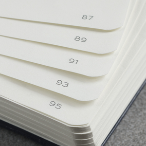 Stack of white papers with numbers printed on them, lying on a textured surface.