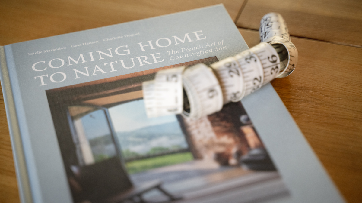 Book titled 'Coming Home to Nature' on a wooden surface with a measuring tape.