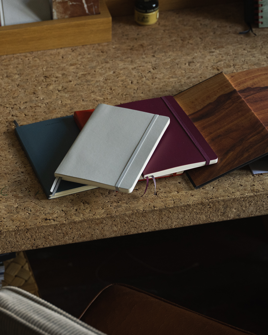 Three notebooks of different colors on a cork surface