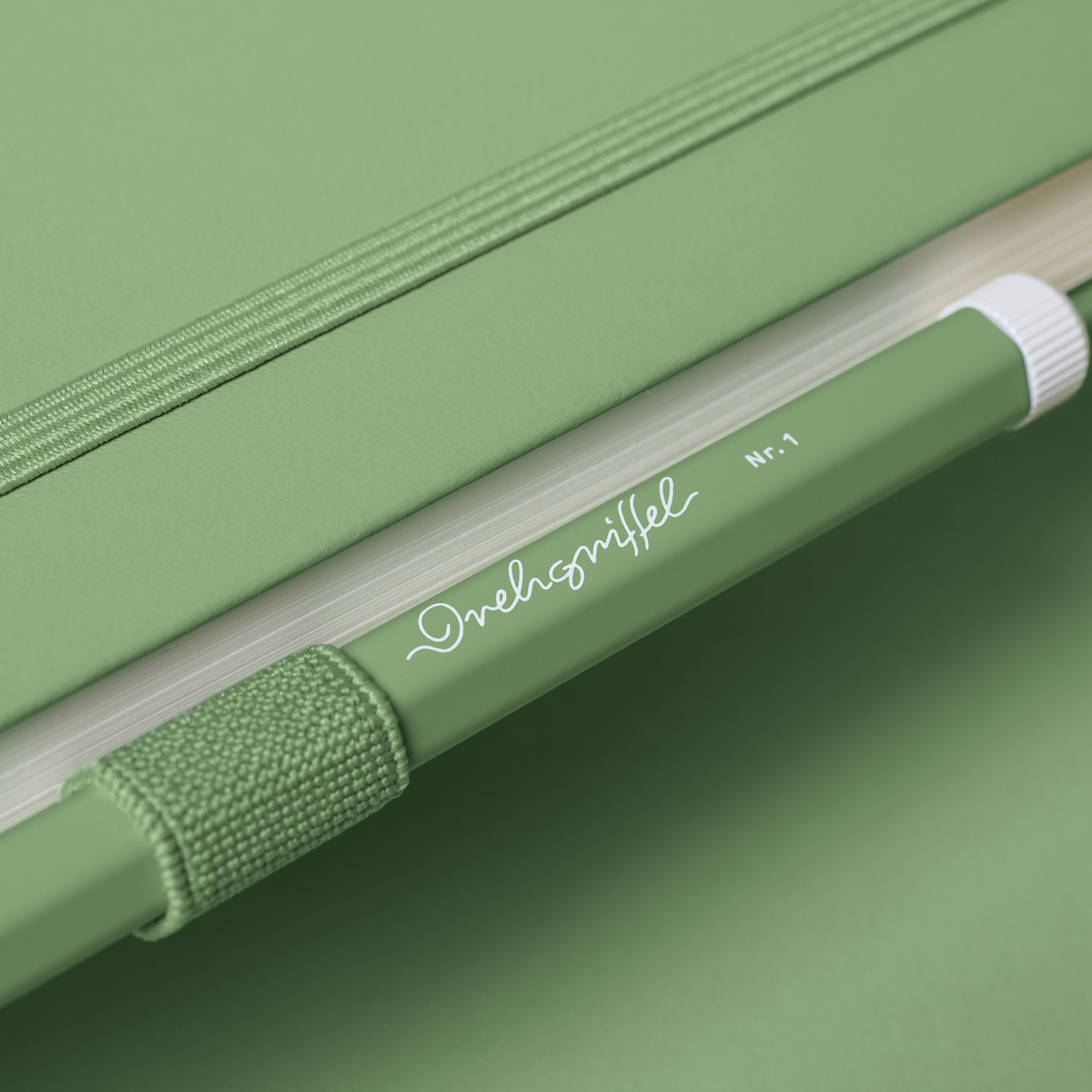 Green notebook with a pen loop on a green background