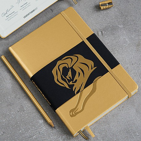 Gold notebook with lion emblem on a gray surface