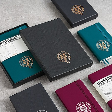 Collection of notebooks with embossed logos on a gray surface