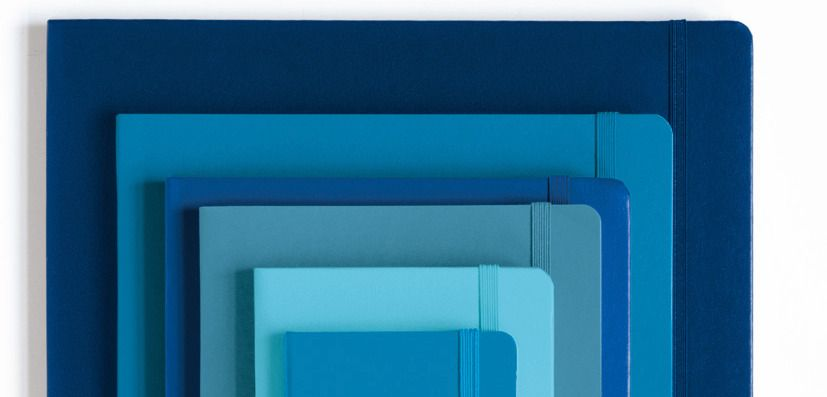 Stack of blue notebooks of different sizes on a white background