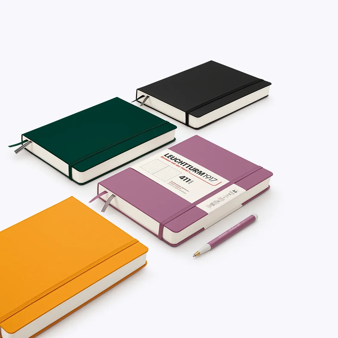 Four colorful notebooks with a pen on a white background