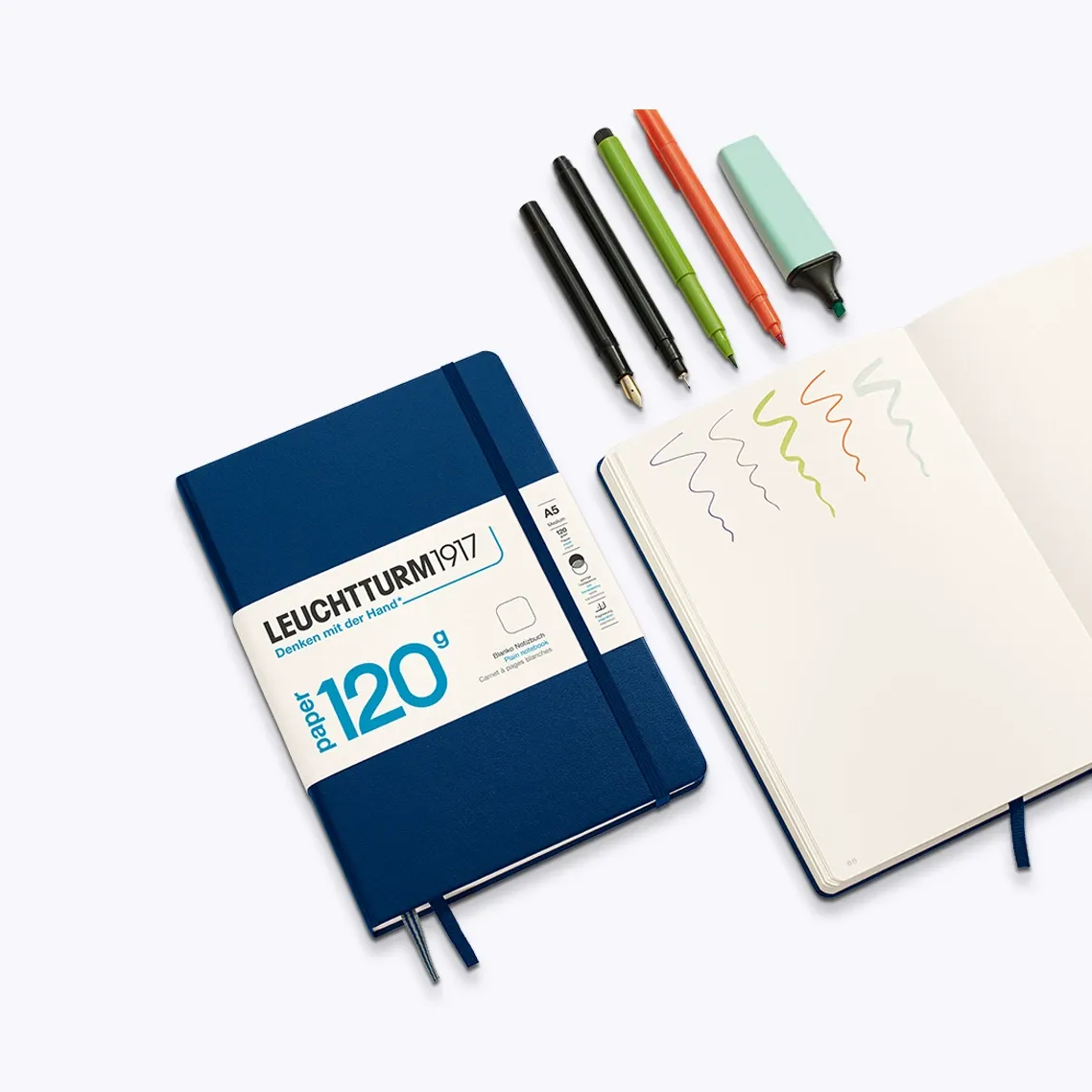 Blue Leuchtturm1917 notebook with a white label, open to a page with doodles, on a white background.
