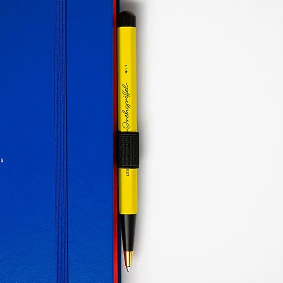 Yellow pen with black cap on a blue notebook