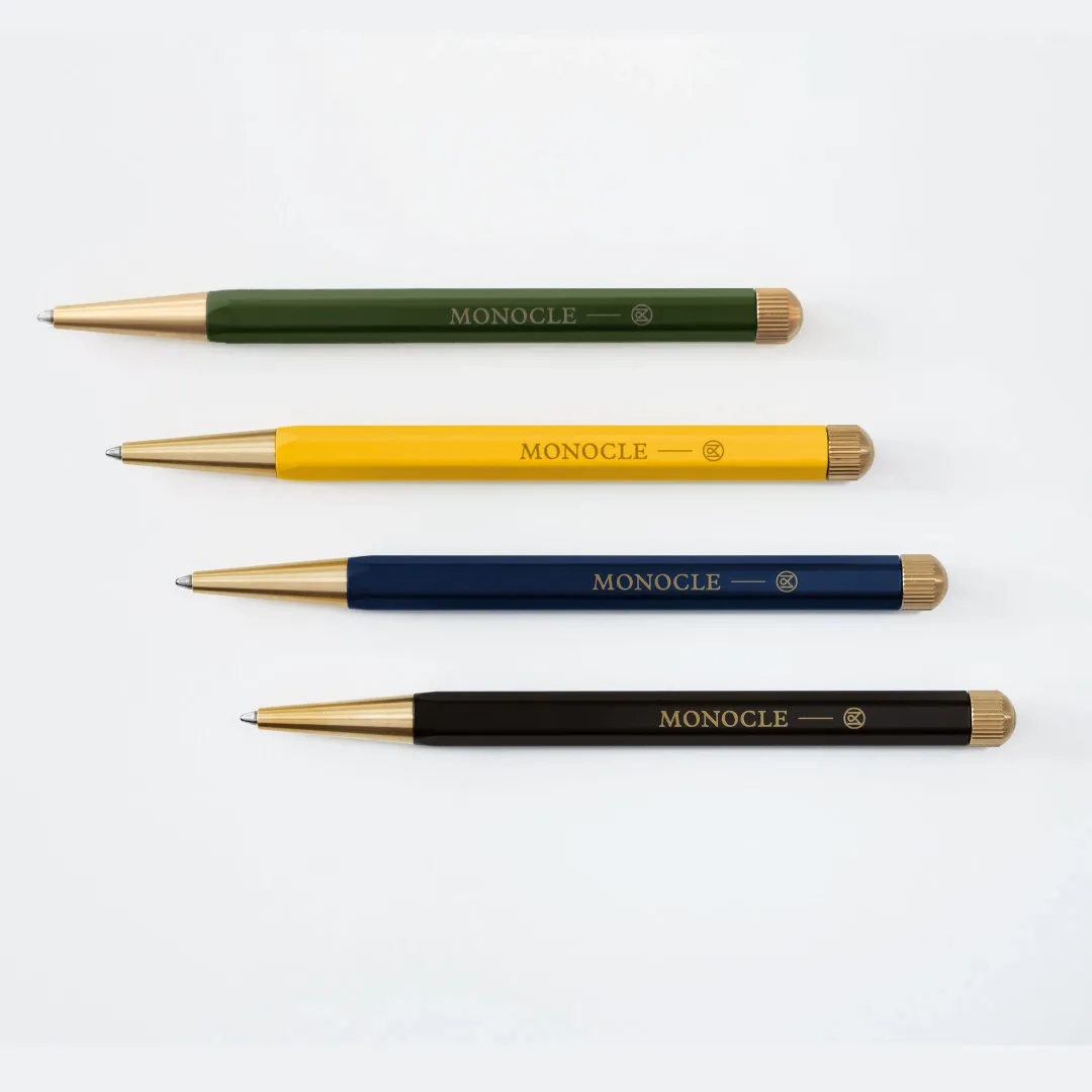 Four pens with different colored barrels and gold accents on a white background, branded 'MONOCLE'.