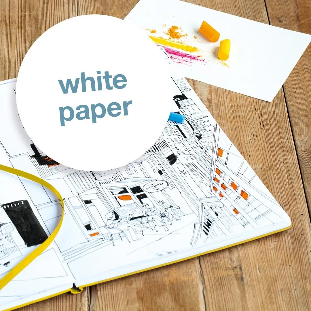 Open book with architectural drawings and a white paper label on a wooden surface