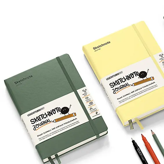 Two sketchnote journals, one green and one yellow, with a pen on a white background.
