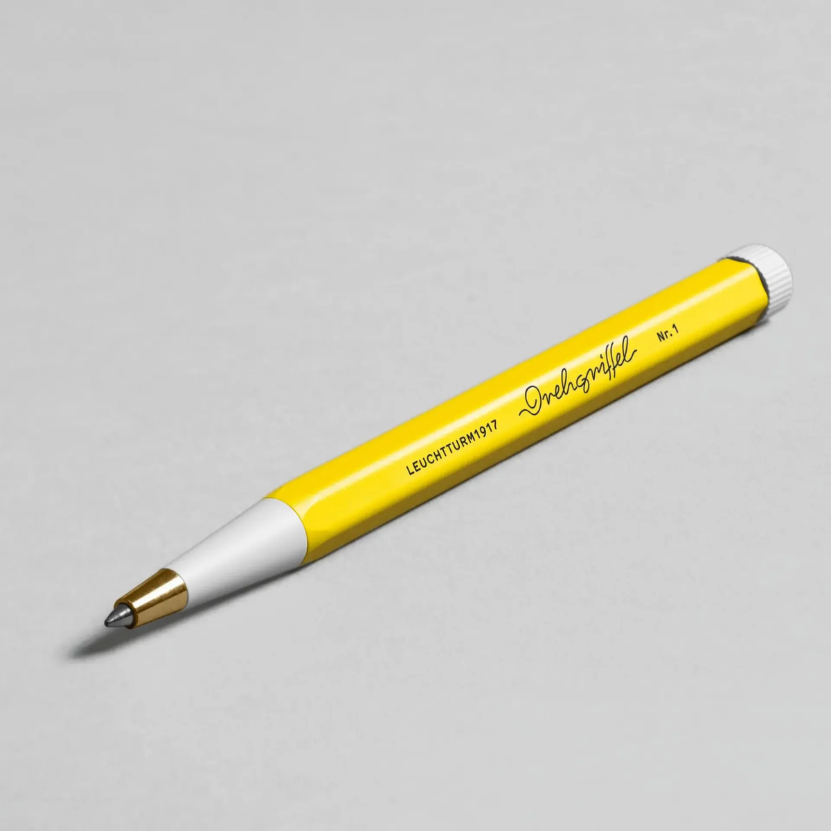 Yellow pen with white cap on a gray background