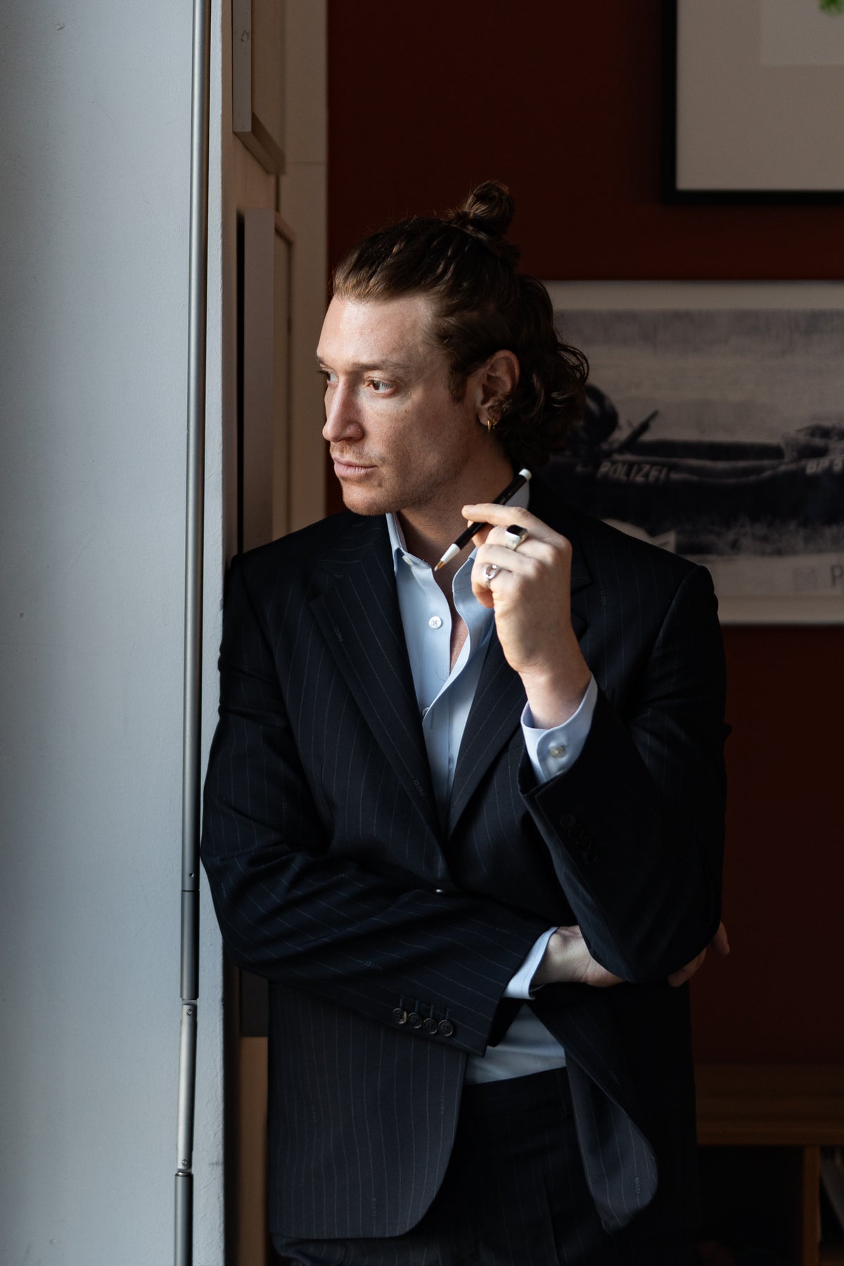 Man in a suit holding a cigarette in an indoor setting