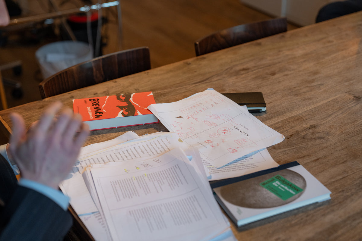 Person interacting with books and a box on a wooden table in a casual setting