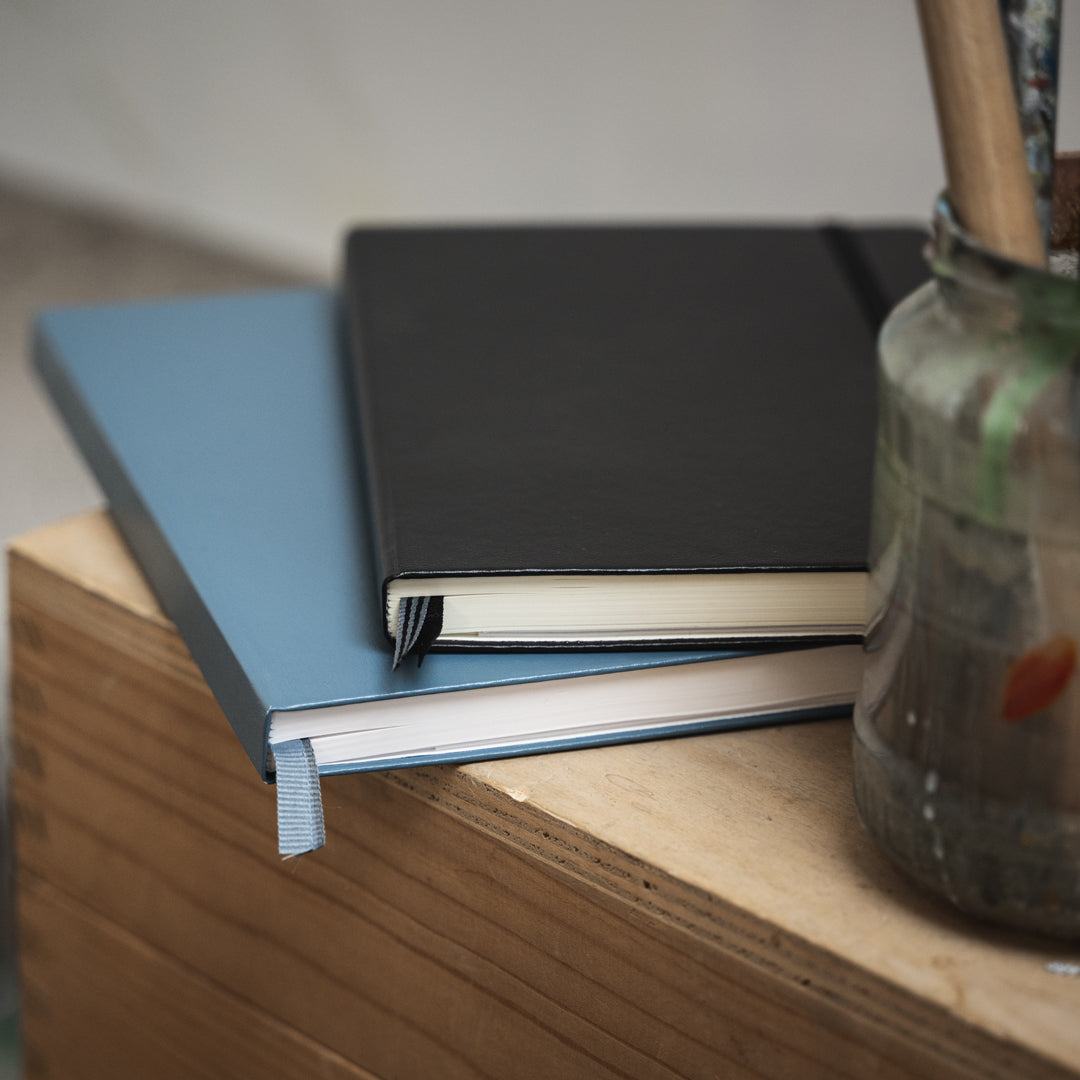 Three notebooks stacked on a wooden surface with a blurred background