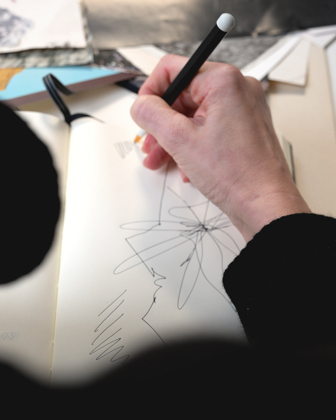 Hand holding a pen over a drawing on a digital tablet with a blurred background